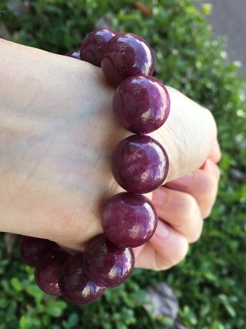 赤紫の大粒の石のブレスレットを着けた手元